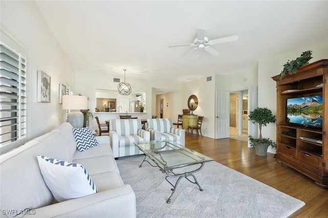 living area with ceiling fan, visible vents, and wood finished floors