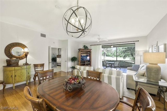 dining room with ceiling fan with notable chandelier, wood finished floors, and visible vents