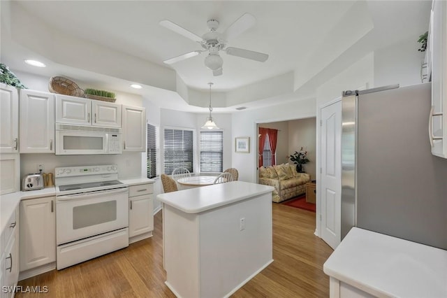 kitchen with white appliances, a kitchen island, light countertops, and light wood finished floors