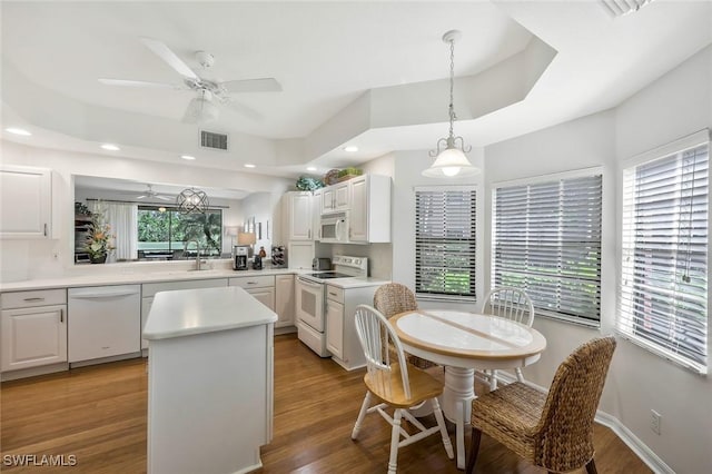 kitchen featuring white appliances, visible vents, a kitchen island, light countertops, and a raised ceiling