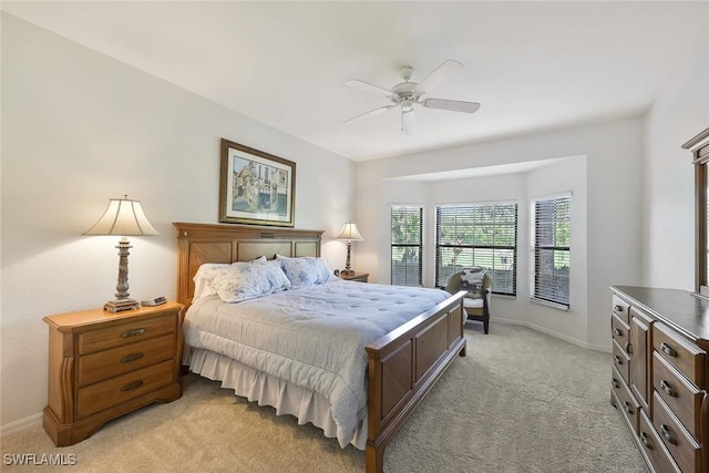 bedroom with a ceiling fan, light colored carpet, and baseboards