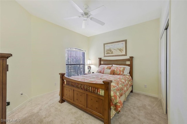 bedroom with ceiling fan, light carpet, baseboards, and a closet