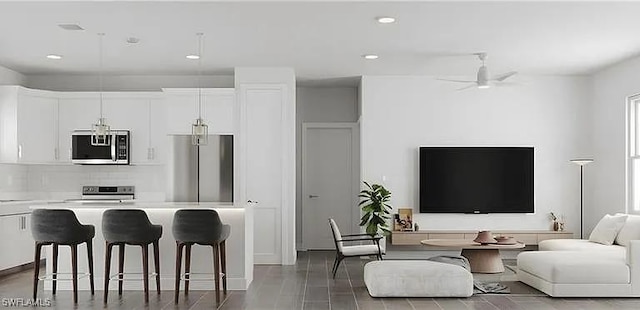 kitchen with a breakfast bar, open floor plan, appliances with stainless steel finishes, white cabinets, and light countertops