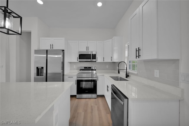 3109 11th St W, Lehigh Acres, FL 33971 - kitchen with light stone countertops, light wood-type flooring, white cabinetry, a sink, and stainless steel appliances