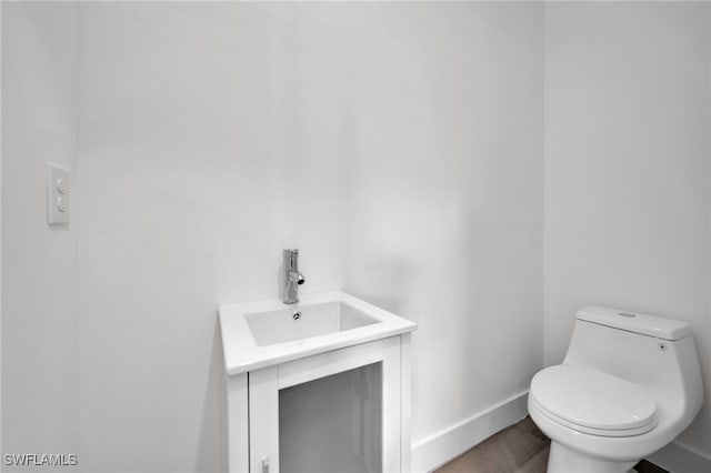 3109 11th St W, Lehigh Acres, FL 33971 - half bathroom featuring baseboards, vanity, toilet, and wood finished floors