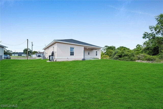 3109 11th St W, Lehigh Acres, FL 33971 - rear view of property with a lawn and stucco siding