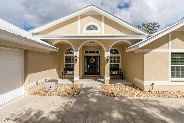 1132 Riverbend Dr, Labelle, FL 33935 - view of exterior entry with a porch, metal roof, an attached garage, and stucco siding