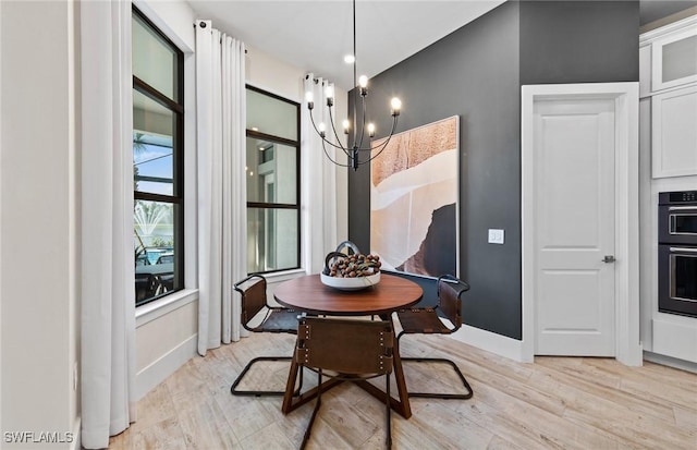 dining space featuring light wood-style floors, baseboards, and a chandelier