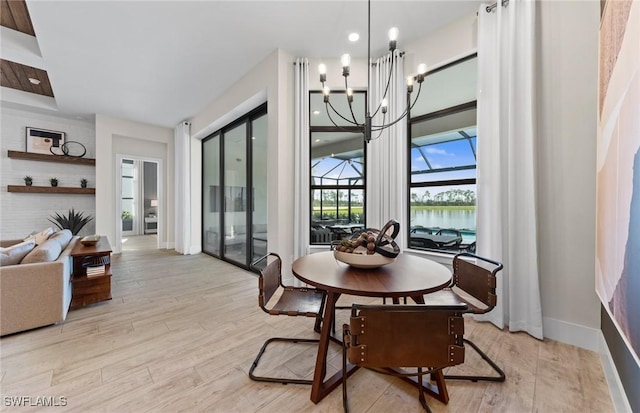 dining room featuring a notable chandelier, light wood-style flooring, a sunroom, and baseboards