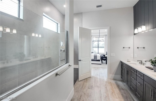 ensuite bathroom with visible vents, ensuite bath, wood finished floors, vanity, and a walk in shower