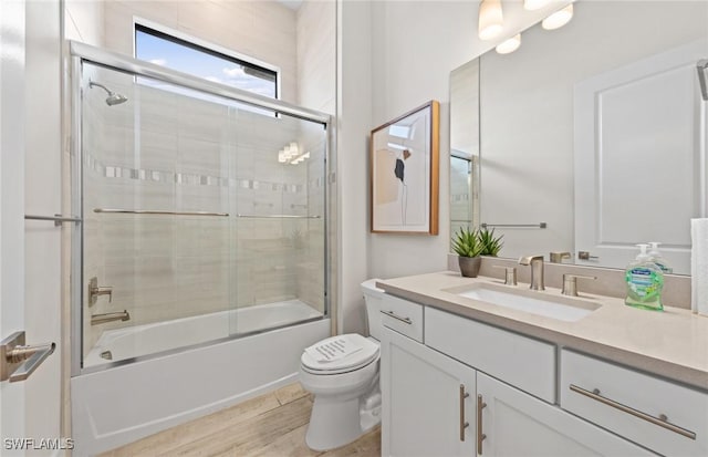 full bathroom featuring combined bath / shower with glass door, vanity, toilet, and wood finished floors