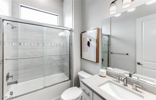 full bath with enclosed tub / shower combo, vanity, and toilet