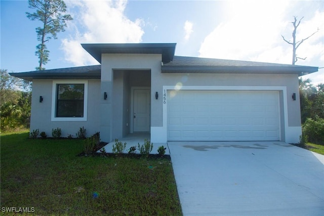 view of front of house with an attached garage, driveway, a front lawn, and stucco siding