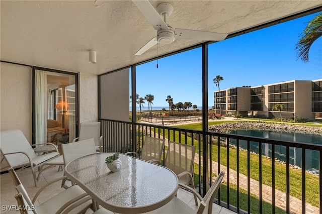 balcony featuring a water view and ceiling fan