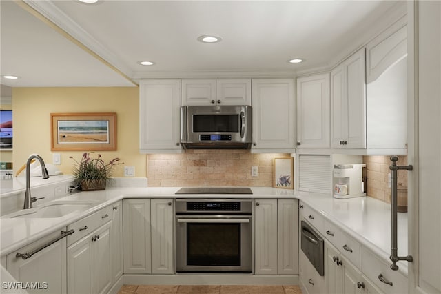 kitchen with a sink, tasteful backsplash, white cabinetry, and stainless steel appliances