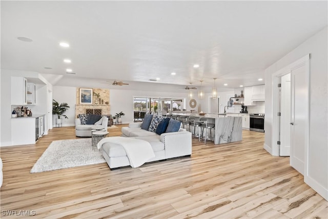 living area with light wood-type flooring, a ceiling fan, and recessed lighting