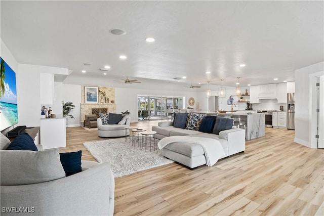 living room with light wood-style floors, baseboards, a ceiling fan, and recessed lighting