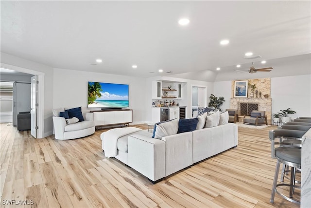 living area with a bar, light wood finished floors, a fireplace, and recessed lighting