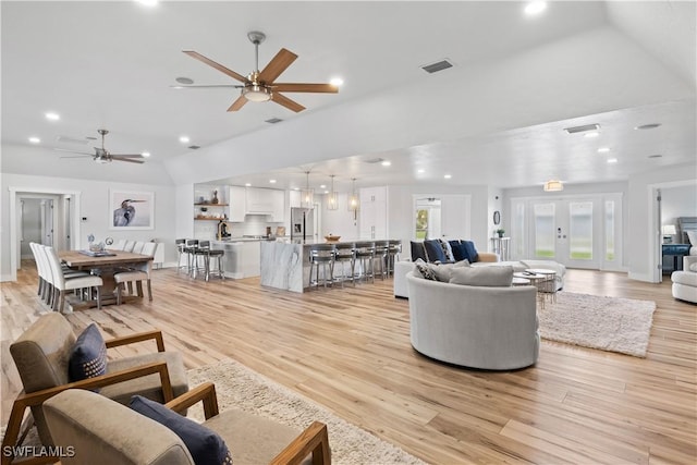 living room featuring lofted ceiling, recessed lighting, visible vents, light wood-style floors, and french doors