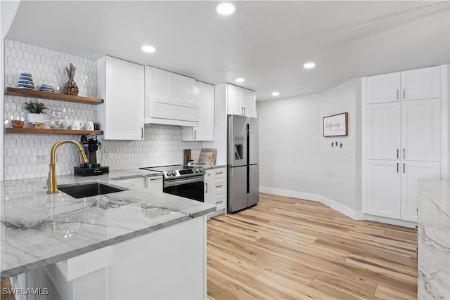 kitchen with light stone countertops, stainless steel appliances, a sink, decorative backsplash, and open shelves