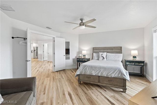 bedroom featuring light wood-style floors, baseboards, visible vents, and stainless steel refrigerator with ice dispenser