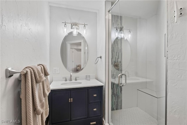 full bathroom featuring a stall shower, a textured wall, and vanity