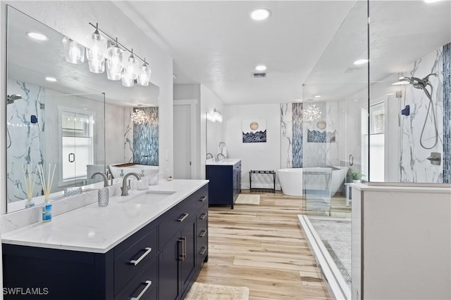 full bathroom featuring a marble finish shower, visible vents, wood finished floors, a freestanding bath, and vanity