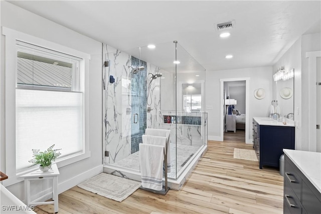 bathroom with a marble finish shower, recessed lighting, visible vents, vanity, and wood finished floors