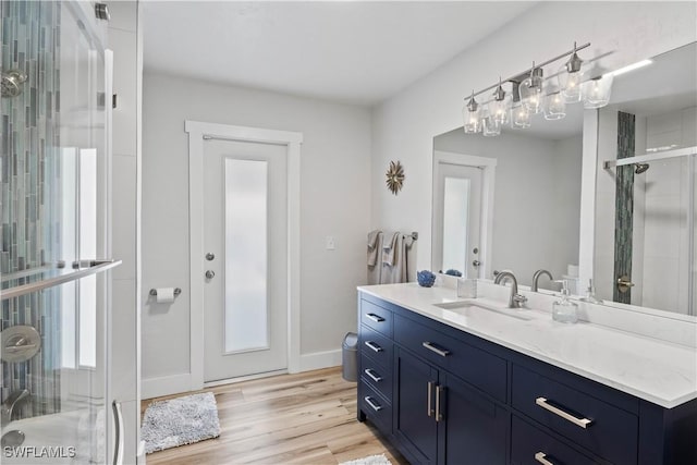 full bath with wood finished floors, a shower stall, vanity, and baseboards