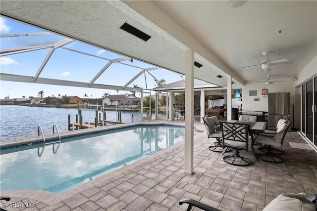 pool featuring a patio, glass enclosure, ceiling fan, a dock, and a water view