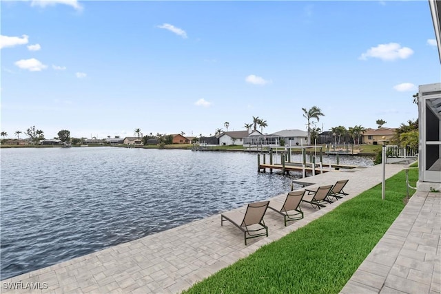 dock area with a residential view, a water view, a lawn, and boat lift