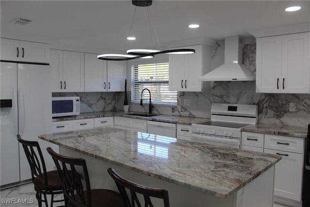 kitchen with a kitchen island, wall chimney range hood, white appliances, white cabinetry, and a sink