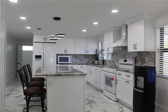 kitchen featuring white appliances, wall chimney exhaust hood, marble finish floor, and a center island