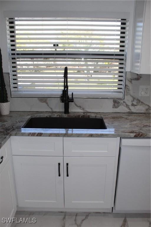 kitchen featuring white cabinetry, decorative backsplash, and a sink