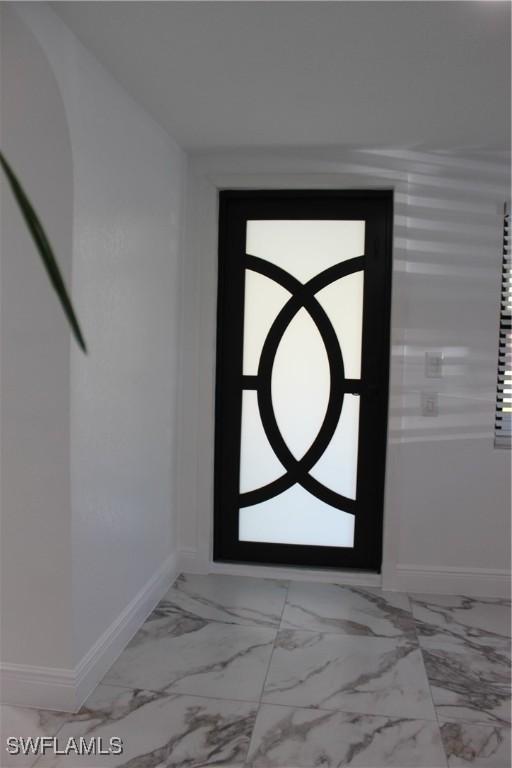 foyer entrance featuring marble finish floor and baseboards