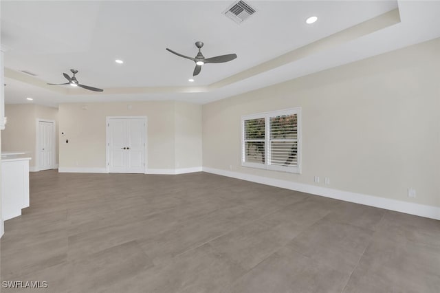 empty room with baseboards, visible vents, a raised ceiling, and recessed lighting