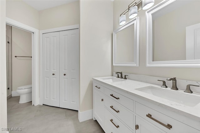 bathroom with toilet, double vanity, a closet, and a sink