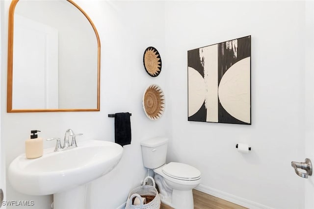 bathroom featuring a sink, wood finished floors, toilet, and baseboards