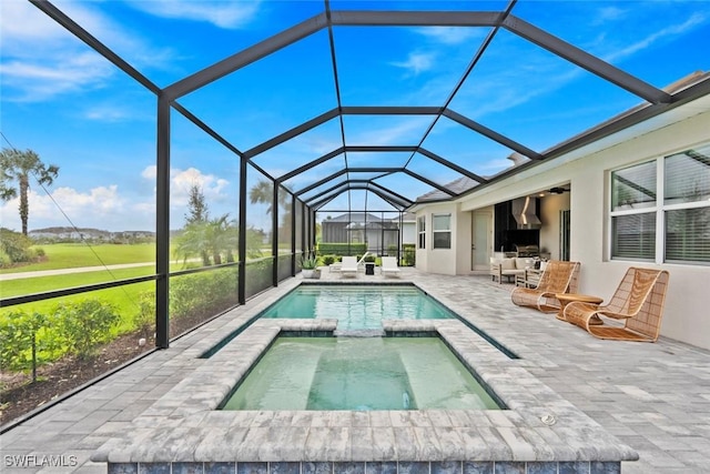 view of pool with a pool with connected hot tub, a patio area, and a lanai