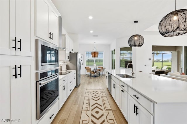 kitchen with stainless steel appliances, recessed lighting, light countertops, light wood-style flooring, and a sink