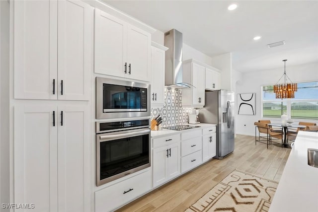 kitchen featuring stainless steel appliances, tasteful backsplash, light countertops, white cabinets, and wall chimney range hood