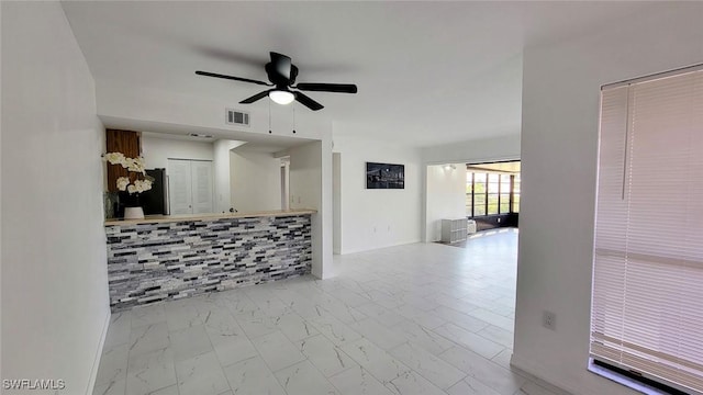 empty room featuring marble finish floor, visible vents, and a ceiling fan