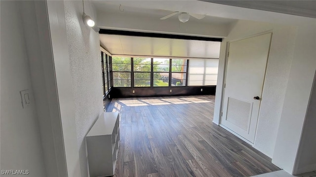 interior space featuring a sunroom, a textured wall, wood finished floors, and visible vents