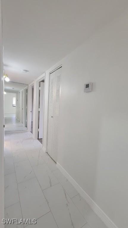 hallway with marble finish floor and baseboards