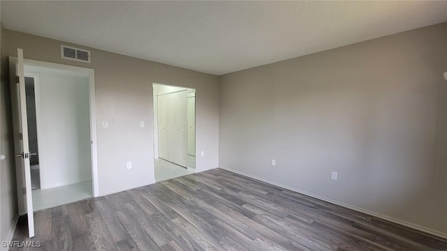 unfurnished bedroom featuring a closet, wood finished floors, and visible vents