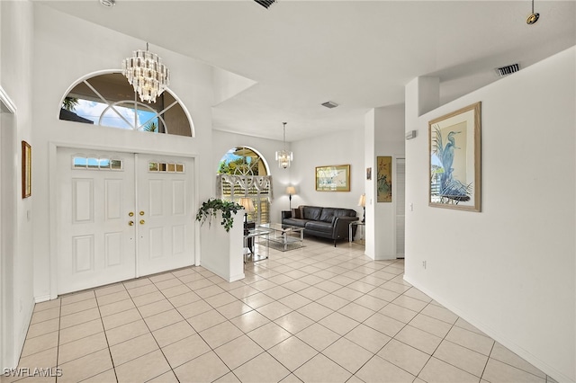 foyer entrance with light tile patterned flooring, visible vents, and an inviting chandelier