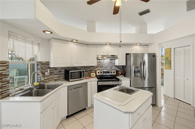 kitchen featuring visible vents, a sink, stainless steel appliances, under cabinet range hood, and backsplash