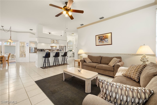 living area featuring light tile patterned floors, ornamental molding, visible vents, and a ceiling fan