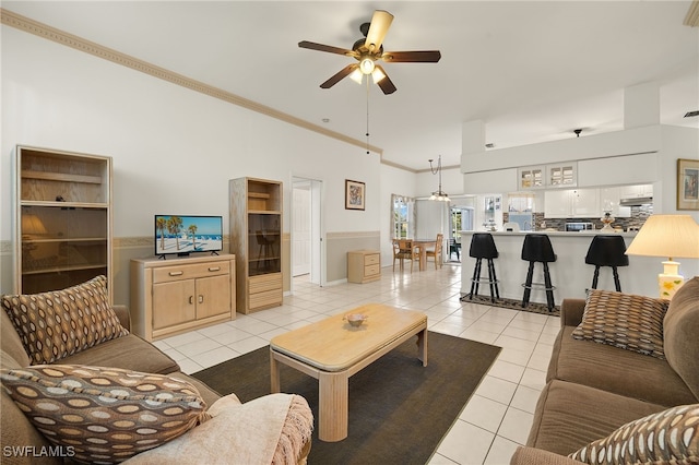 living room with light tile patterned floors, ornamental molding, and a ceiling fan