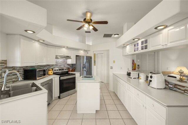 kitchen featuring stainless steel appliances, decorative backsplash, light tile patterned flooring, a sink, and under cabinet range hood